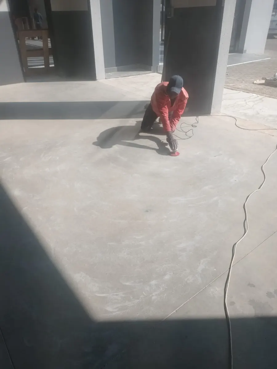 Installer working across a bare concrete floor with a corded tool before the epoxy goes down