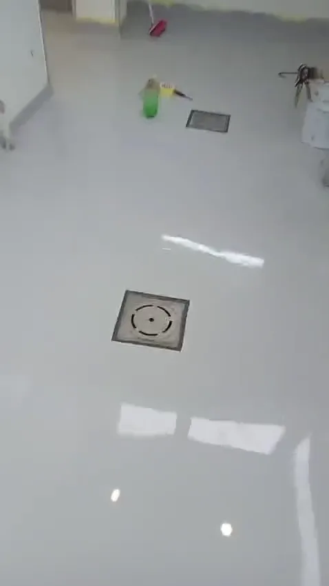 Close-up of a square metal floor drain set into a light-grey gloss epoxy floor