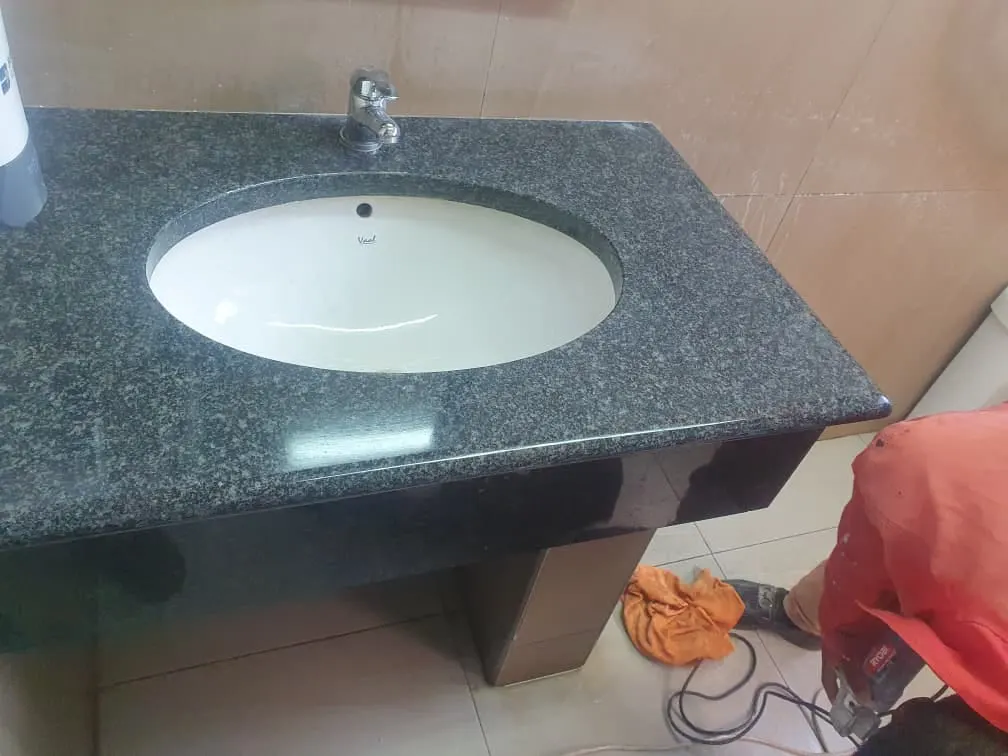 Dark granite basin vanity with an undermount sink after polishing