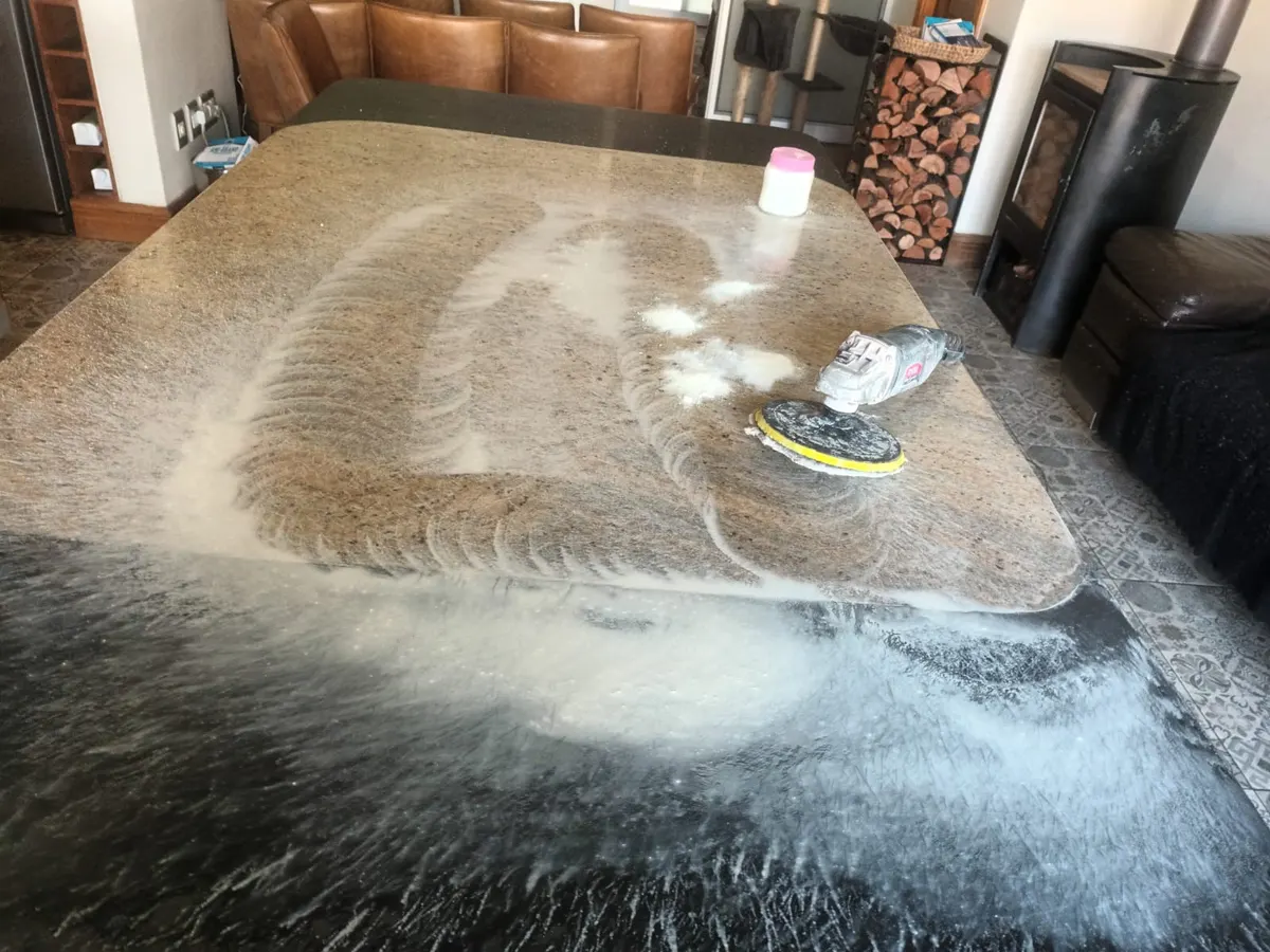 Granite table top covered in polishing slurry with a polishing pad on it