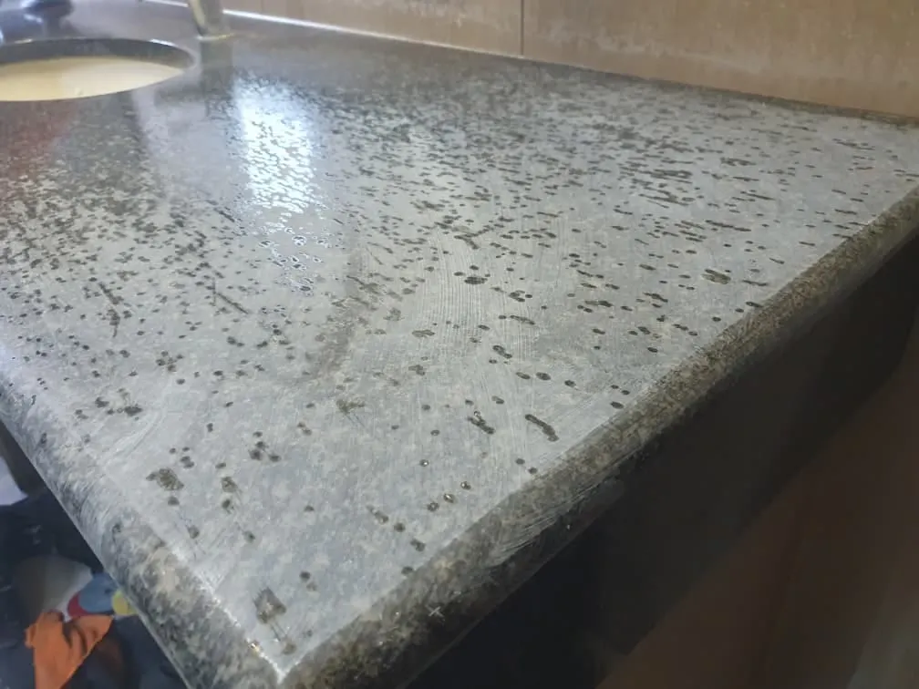 Dull, water-marked granite vanity top before restoration