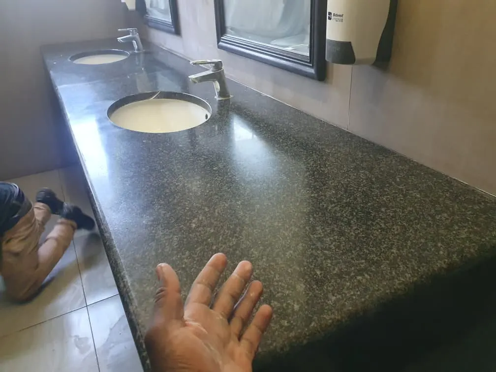 Polished granite vanity top reflecting the taps and mirror