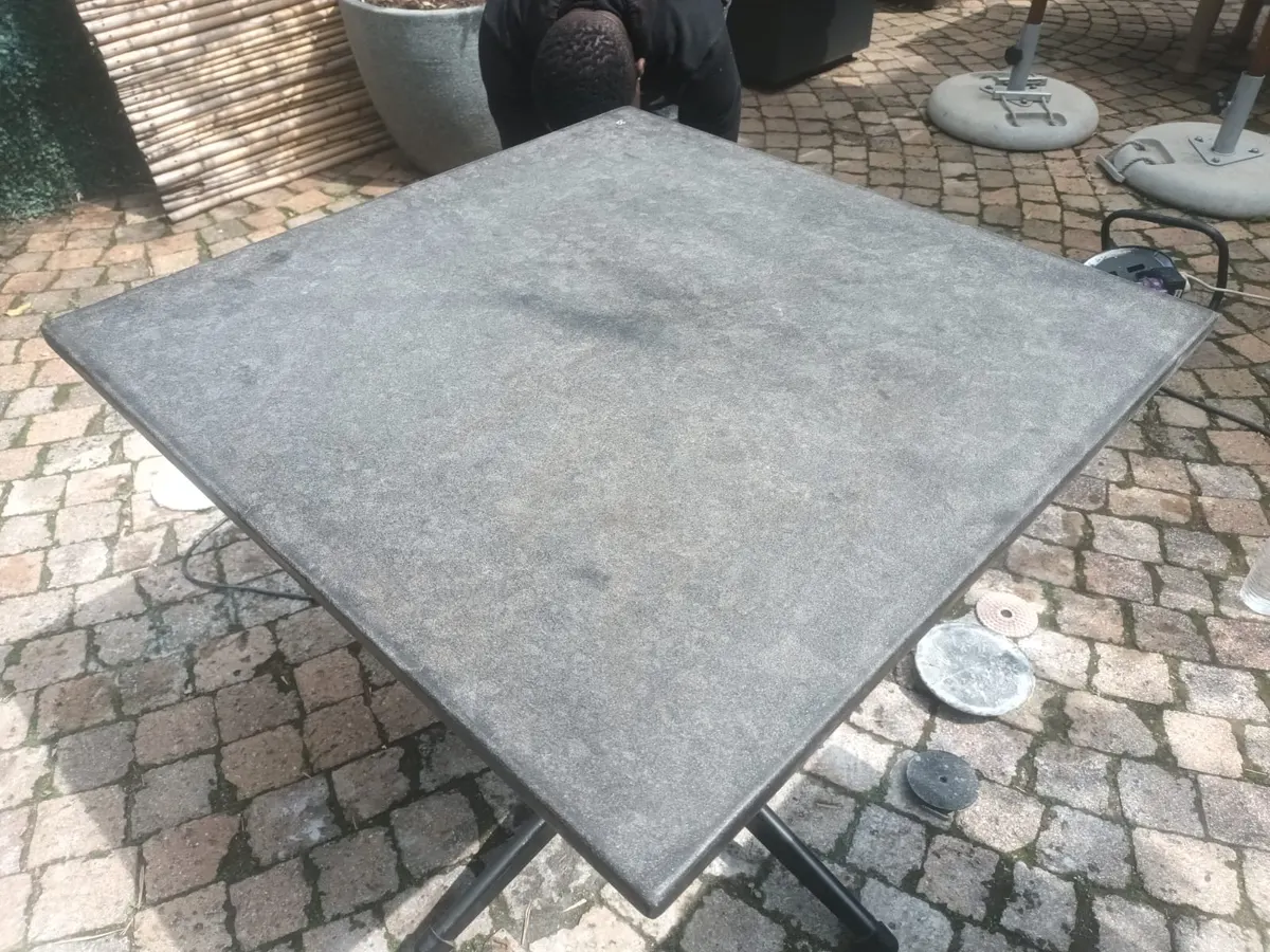 Weathered dark stone outdoor table top before restoration