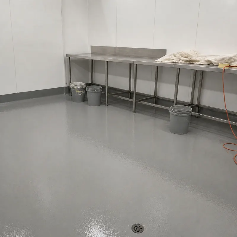 Finished seamless grey hygienic epoxy floor with coved skirting in a food-production room